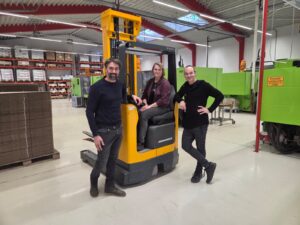 Mitarbeiterin Andrea Rosenitsch auf dem Gabelstapler. Links und rechts davon stehen die Geschäftsführer Michael und Erwin Mach.